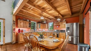 A kitchen with wooden cabinets, a stainless steel refrigerator, and a dining table set for four. - Pet-friendly, Stocked Fishing Pond, Hiking (Nineveh)
