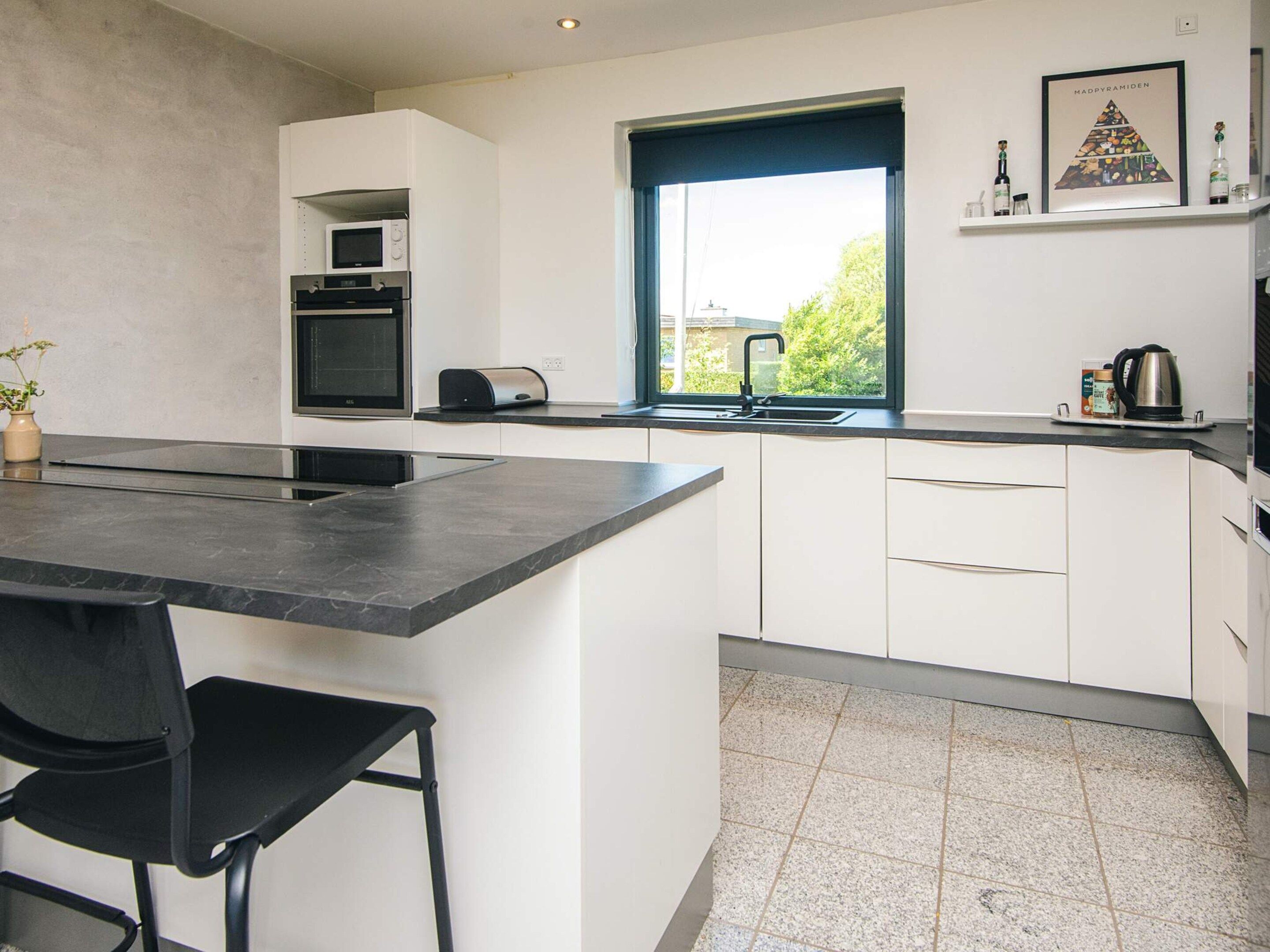 A modern kitchen with a central island, a built-in oven, and a window with a view.
