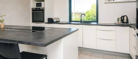Una cocina moderna con una isla central, horno empotrado y ventana con vistas.