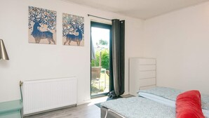 Un dormitorio con cama, escritorio, radiador y dos cuadros en la pared.