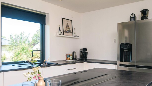 Una cocina moderna con una isla grande, electrodomésticos de acero inoxidable y un ventanal con vistas al verdor.
