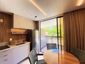 Une cuisine moderne avec un coin repas, de grandes fenêtres et un balcon.