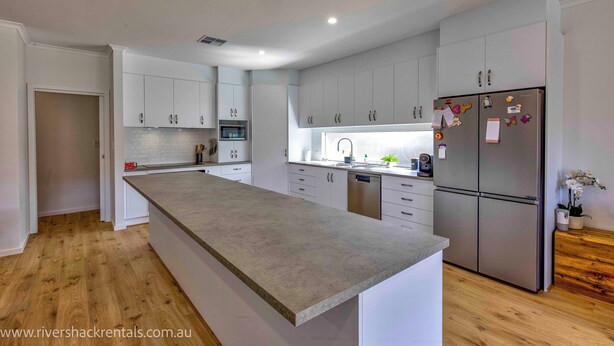 A modern kitchen with white cabinets, a stainless steel refrigerator, and a wooden floor. - 142 Page Drive - Alls Well (Blanchetown)