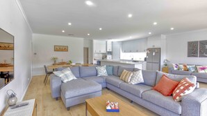A modern living room with a grey sectional sofa, a wooden coffee table, and a dining area with a wooden table and chairs. - 142 Page Drive - Alls Well (Blanchetown)