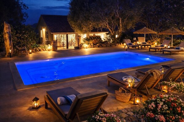A swimming pool with lounge chairs and a small building with a tiled roof.