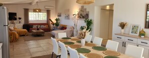 A modern living room with a sofa, coffee table, and dining area with a table set for four. - Villa Roccapina - Exceptional villa with private pool near Roccapina (Sartène)