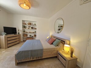 Ein Schlafzimmer mit einem Bett, Nachttischen, einem Fernseher, einer Ablage mit Dekoration und einem Spiegel.