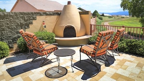 An outdoor patio with a stone-tiled floor, a brick oven, and striped chairs. - Getaways at Highlands at Verde Ridge (Cornville)