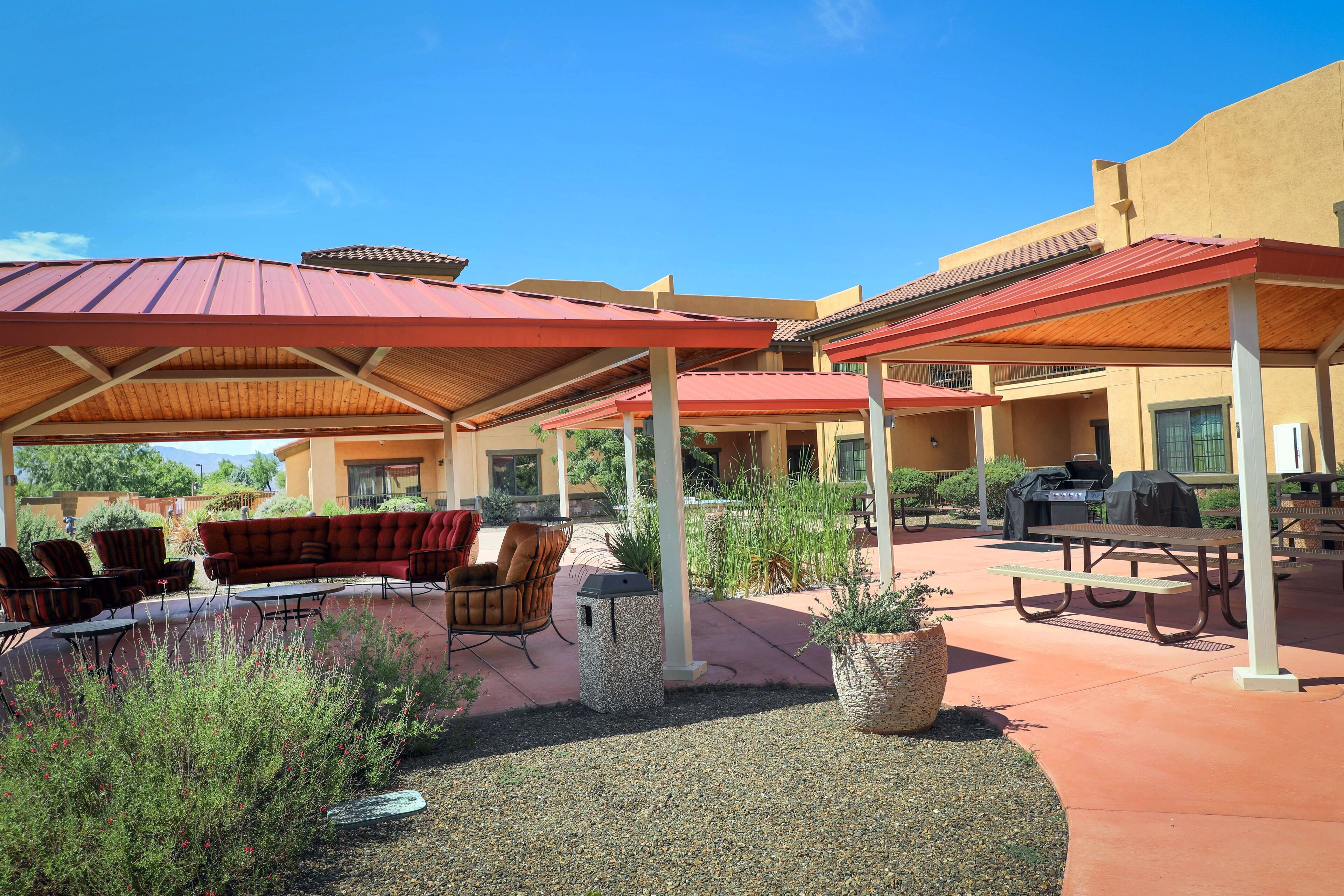 An outdoor patio area with covered seating, a barbecue grill, and a pool.