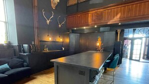 A modern kitchen with a central island, wooden cabinets, and antler wall decor. - The Old Church Isle of Bute (Rothesay)