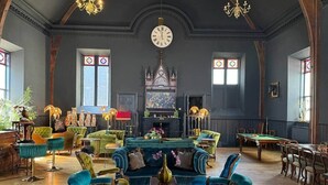 A spacious room with a large clock, a fireplace, and multiple seating areas. - The Old Church Isle of Bute (Rothesay)