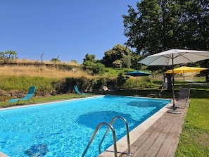 Piscina com água azul cristalina, rodeada por espreguiçadeiras e guarda-sóis.