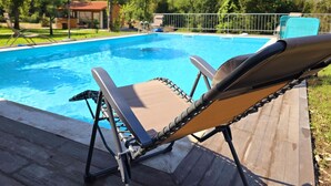Ein Poolbereich mit Liegestuhl, Pool und Sonnenschirm.