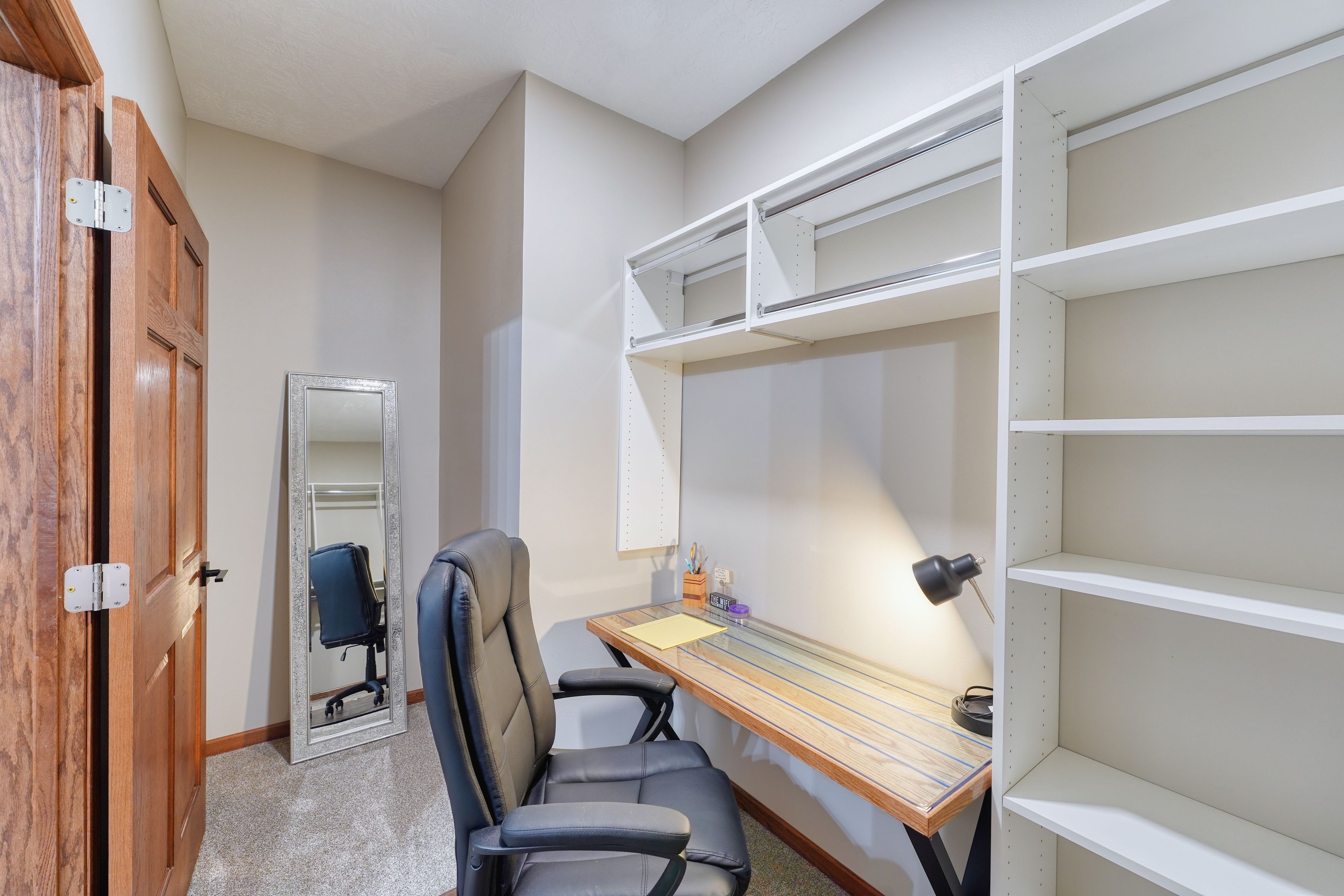 A small office space with a desk, chair, and shelving unit.