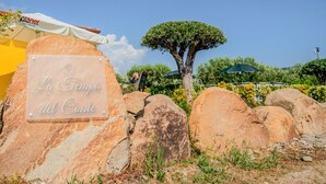 A sign reading "La Tropa del Conte" surrounded by large rocks and a tree.