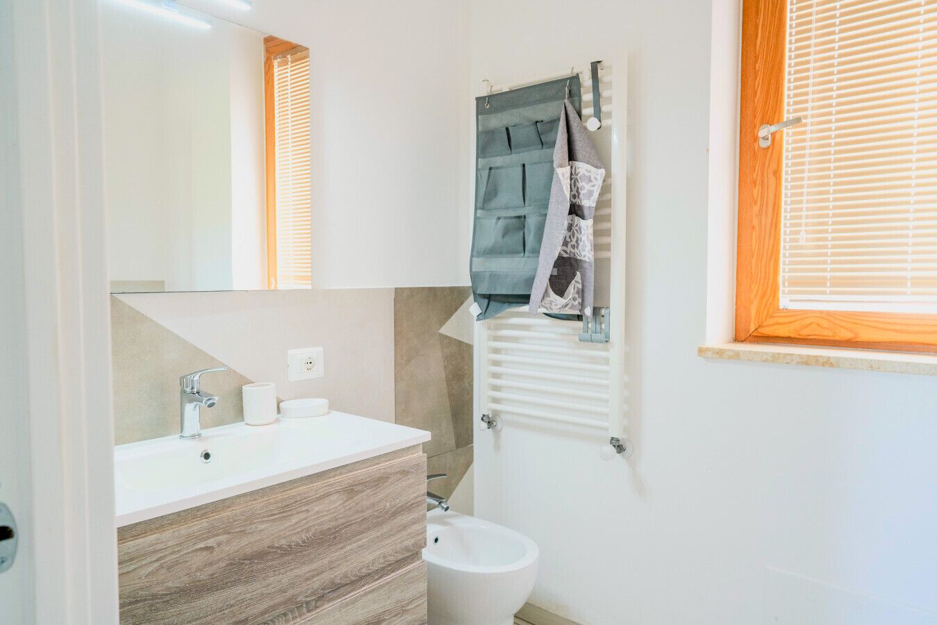 Une salle de bain avec un lavabo blanc, un miroir, un porte-serviettes et des toilettes.
