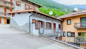 Un bâtiment traditionnel avec une façade en pierre, des volets en bois et un balcon doté d’une rambarde en métal.