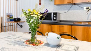 Une cuisine avec des meubles en bois, un four à micro-ondes et un vase rempli de fleurs sur la table.