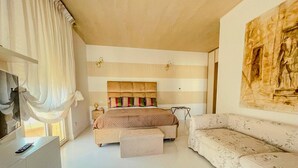 Een ruime slaapkamer met een groot bed, een bank en een schilderij aan de muur.