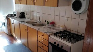 Una cocina con armarios de madera, estufa a gas, microondas y lavaplatos.