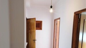 Un pasillo con puertas de madera, una lámpara y una alfombra estampada.