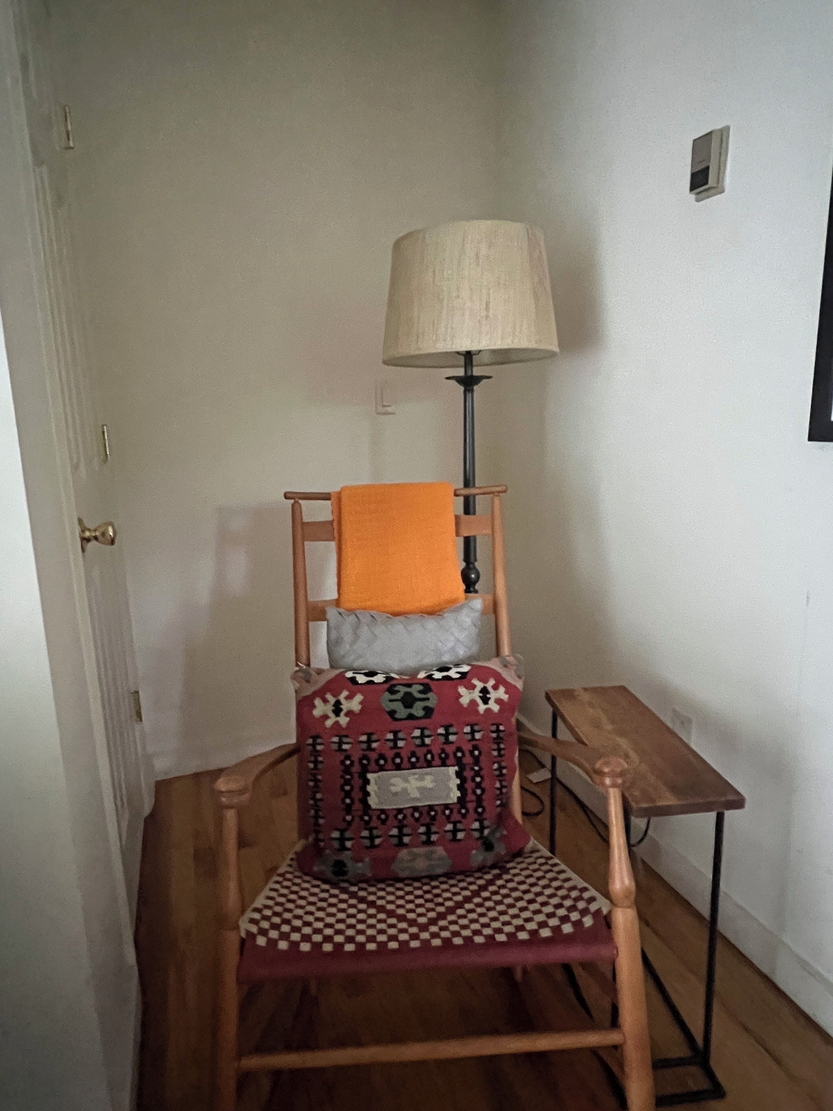 Une chaise en bois avec un coussin à motifs et une table à carreaux placée à côté.