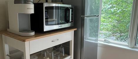 Cocina pequeña equipada con microondas, hervidor y refrigerador.