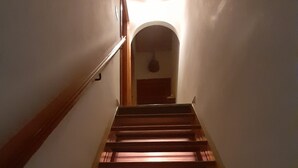 A narrow staircase with wooden steps and a handrail on the left, leading to a landing with a door at the top.