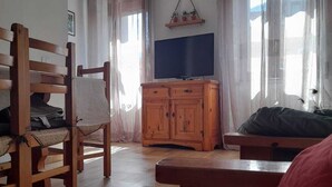 A room with a wooden chair, a wooden cabinet, a television, and a bed.