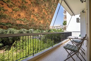 A balcony with a metal railing, a table, and two folding chairs. - Urban Nest In Chalandri by MΡS (Chalandri)