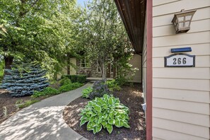 A house with a number 266 sign, a stone chimney, and a well-maintained garden with a pathway.