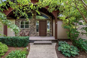 A house with a stone facade, a brown front door, and a porch with a bench.
