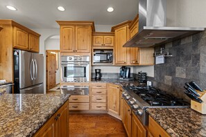 A kitchen with wooden cabinets, stainless steel appliances, granite countertops, and a gas stove.