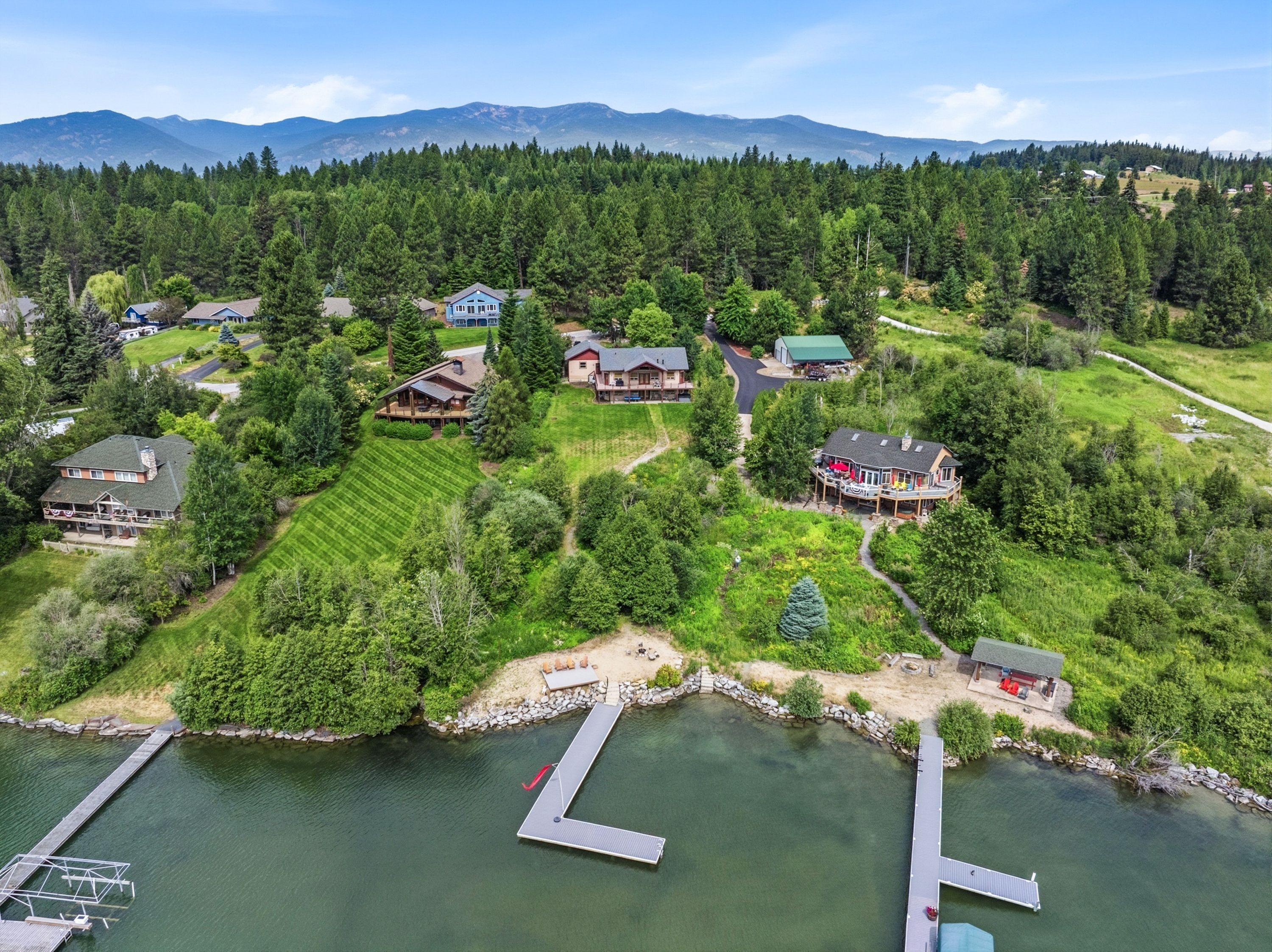Une propriété au bord du lac comprenant plusieurs maisons, des quais et un paysage boisé en arrière-plan.