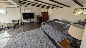 A bedroom with a bed, a television, a fireplace, and a window. - The Cottage at River's Bend (Howard)