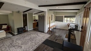 A spacious living area with a large rug, a bench, and a wooden stand. - The Cottage at River's Bend (Howard)