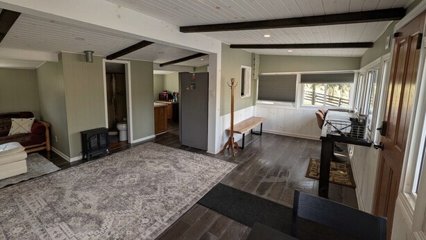 A spacious living area with a large rug, a bench, and a wooden stand. - The Cottage at River's Bend (Howard)