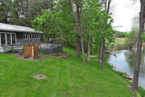 A house with a deck, a fenced yard, and a river.