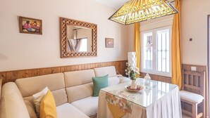 Una sala de estar acogedora con un sofá, una mesa de centro de vidrio y un espejo decorativo.