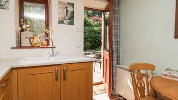 A kitchen with wooden cabinets, a white sink, and a window overlooking a garden.