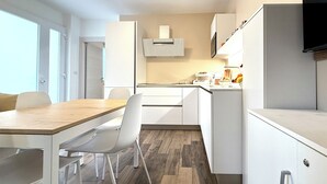 Een moderne keuken met witte kasten, een houten eettafel en een inbouwoven.