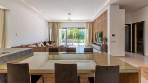 Un espace repas moderne avec une table en verre, des chaises en bois et une vue sur l’extérieur.