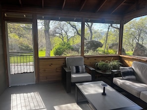 A covered outdoor seating area with a view of a wooded landscape, a bench, a sofa, and a coffee table. - 3-bedroom house in tranquil Three Rivers with WiFi, AC. Enjoy nature (Three Rivers)