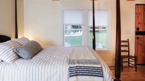 Ein Schlafzimmer mit Bett, Kissen, einem Fenster mit Aussicht und einer Holztür.