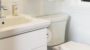 Ein Badezimmer mit einem weißen Waschbecken, einer Toilette und einer Handseifenflasche.