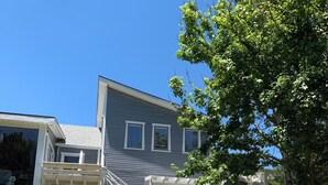 A two-story house with a covered porch, a staircase, and a small garden area. - Argyles Too! A brand new Loft Efficiency (Kitty Hawk)