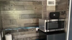 A compact kitchen with a built-in microwave, a stainless steel refrigerator, and a marble countertop. - Argyles Too! A brand new Loft Efficiency (Kitty Hawk)