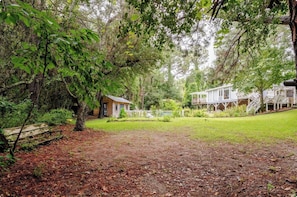 A wooded area with a small cabin and a larger house with a porch. - Argyles Too! A brand new Loft Efficiency (Kitty Hawk)
