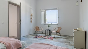 Quarto com cama, uma pequena mesa e cadeiras, radiador e janela com vista.
