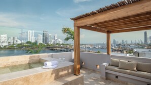 A rooftop terrace with a wooden pergola, a hot tub, and a seating area with cushions. - Casa Sonara (Cartagena)